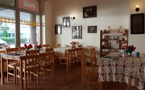 Sala pierogarni: drewniane stoły i krzesła, obrazki na ścianach